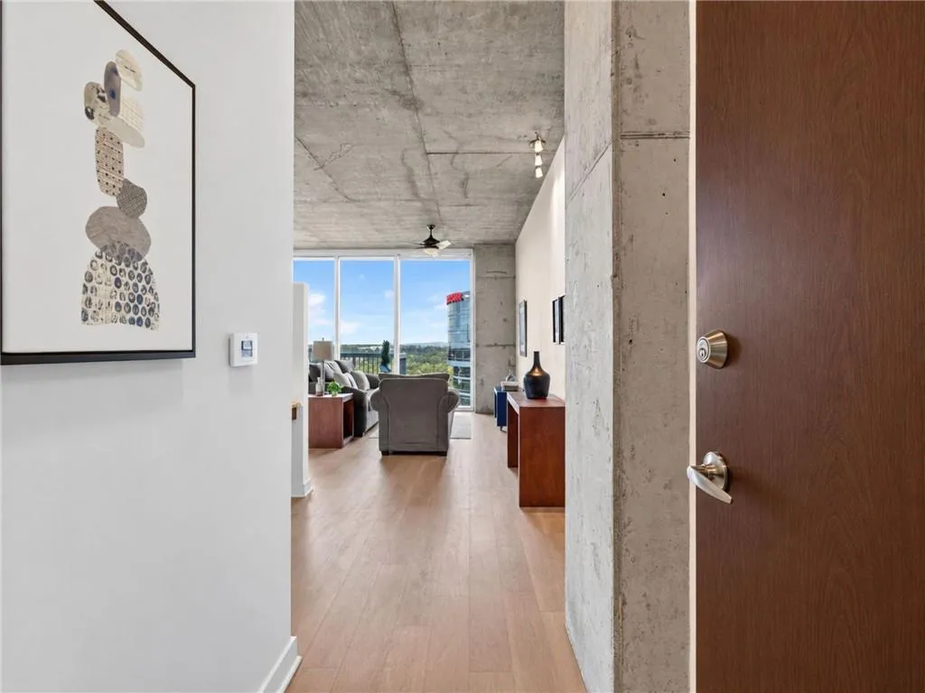Entry way. Concrete ceiling, light wood-finish flooring with floor to ceiling windows.