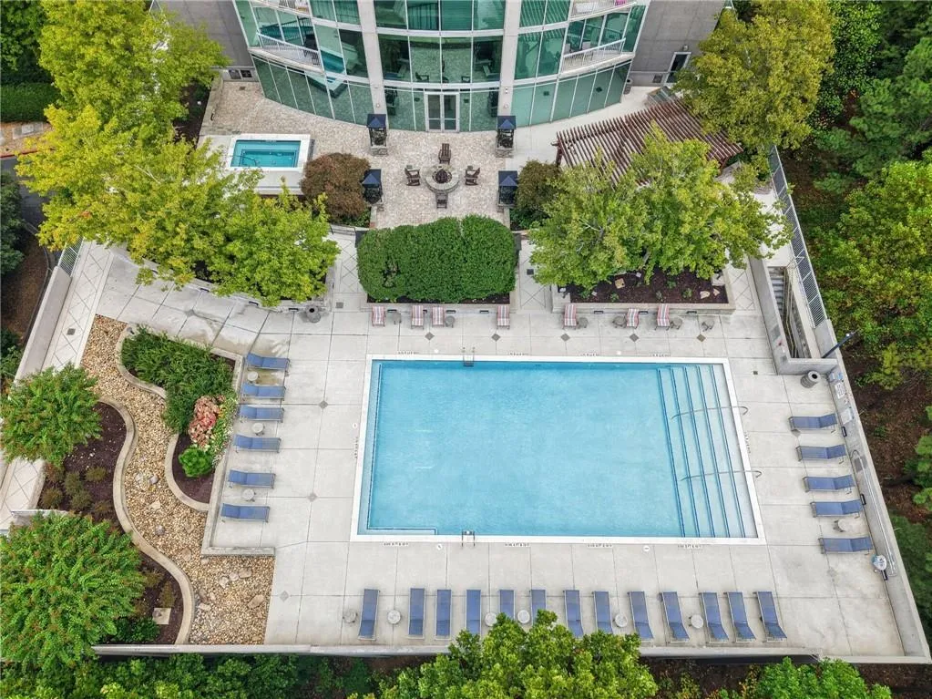 Outdoor swimming pool with integrated steps, surrounding lounge areas, and elevated hot tub