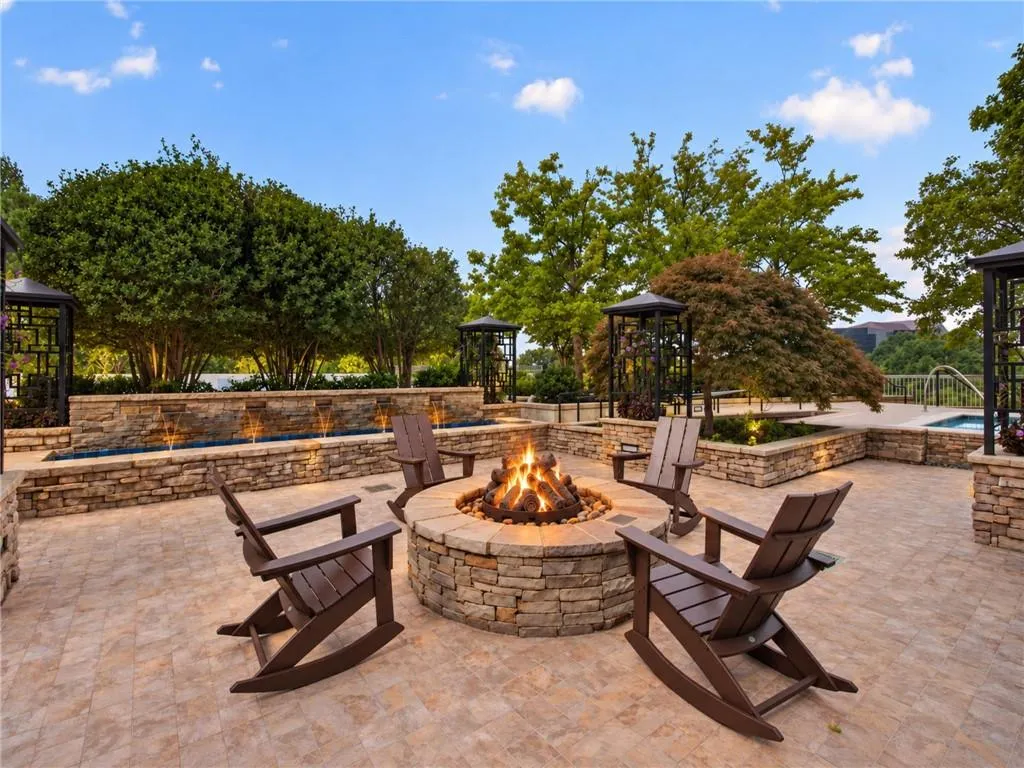 Stone-clad fire pit, expansive paver patio, integrated water features, stone retaining walls, and mature landscaping