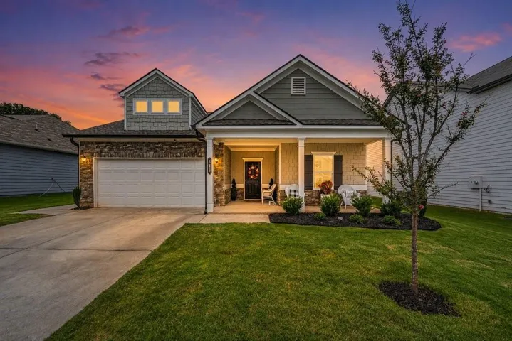 Craftsman-style exterior featuring a covered front porch, stone accents, shingle siding, a two-car garage, and a concrete driveway