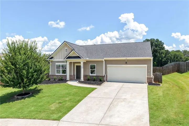 Craftsman-style exterior with gabled roofline, front-facing garage, concrete driveway, and front landscaping