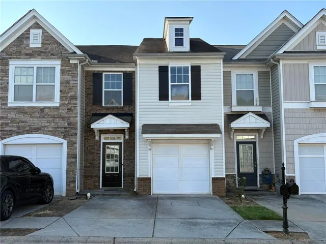 Multi-story townhouse with varied exterior finishes, including stone veneer, brick, and horizontal siding