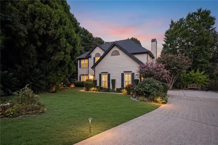 Siding exterior, dark shingle roof, established landscaping, concrete driveway, and exterior lighting