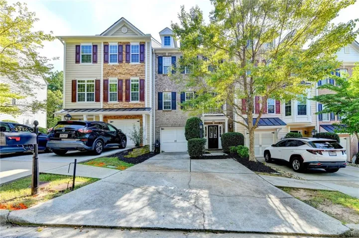 Three-story facade with stone and siding accents, prominent gabled roofline, and attached two-car garage