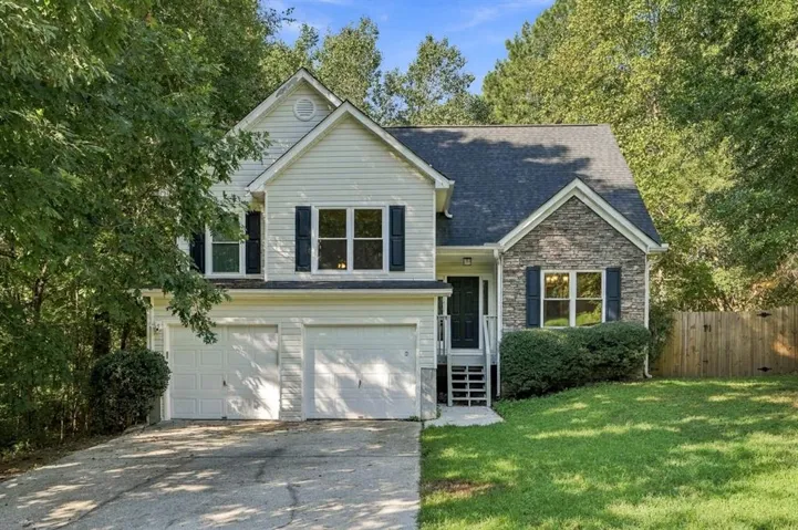 Two-story property with light-colored siding, a dark shingle roof, and a stone facade accent