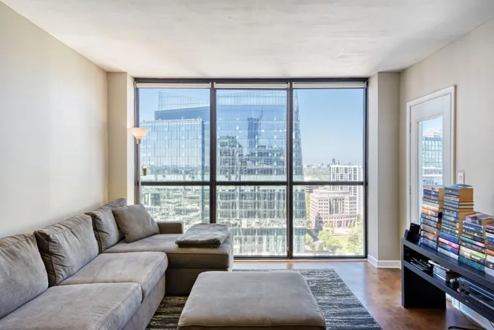 Living room with finished concrete floors, a city view, healthy amount of natural light, and floor to ceiling windows