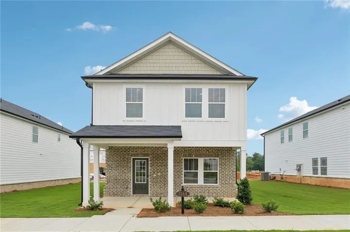 Two-story residence featuring a covered front porch with white columns, a brick facade, and vertical white siding