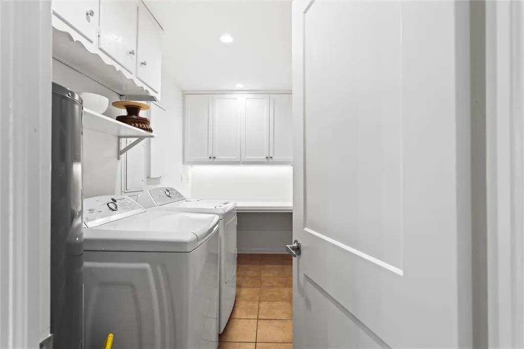 Laundry area with light tile patterned flooring, cabinet space, washing machine and clothes dryer, recessed lighting, and water heater