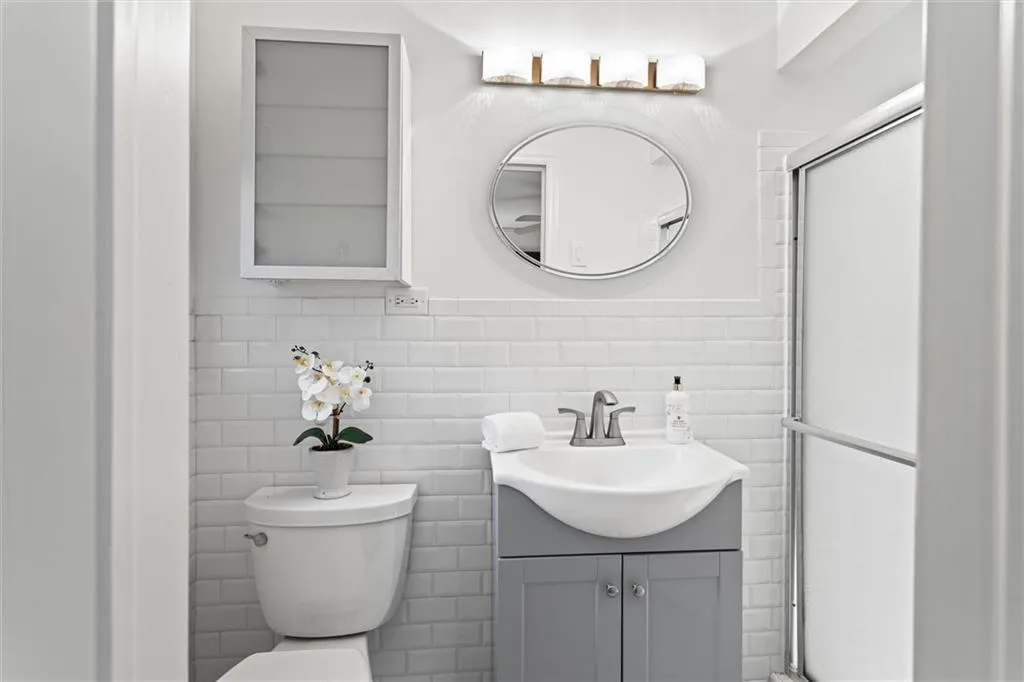 Full bathroom featuring tile walls, vanity, a shower stall, and wainscoting