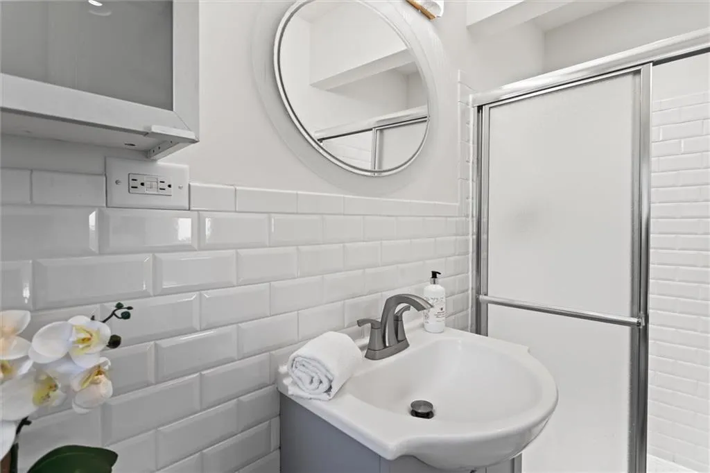 Bathroom with tile walls, vanity, a stall shower, and a wainscoted wall