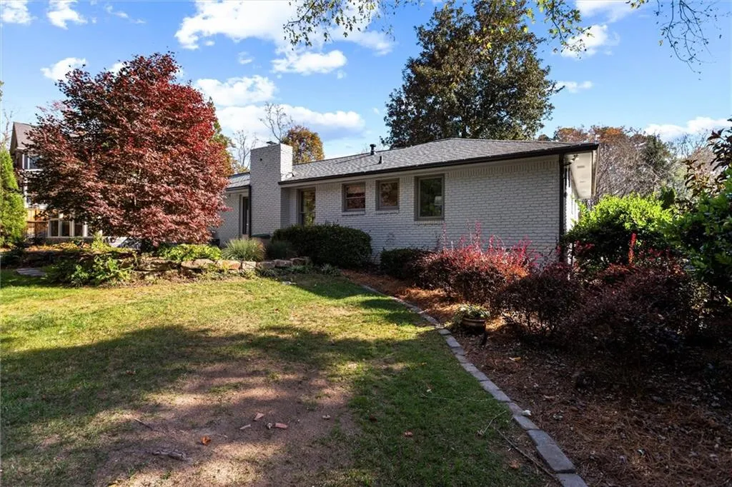 Rear view of property with a yard, brick siding, and a chimney