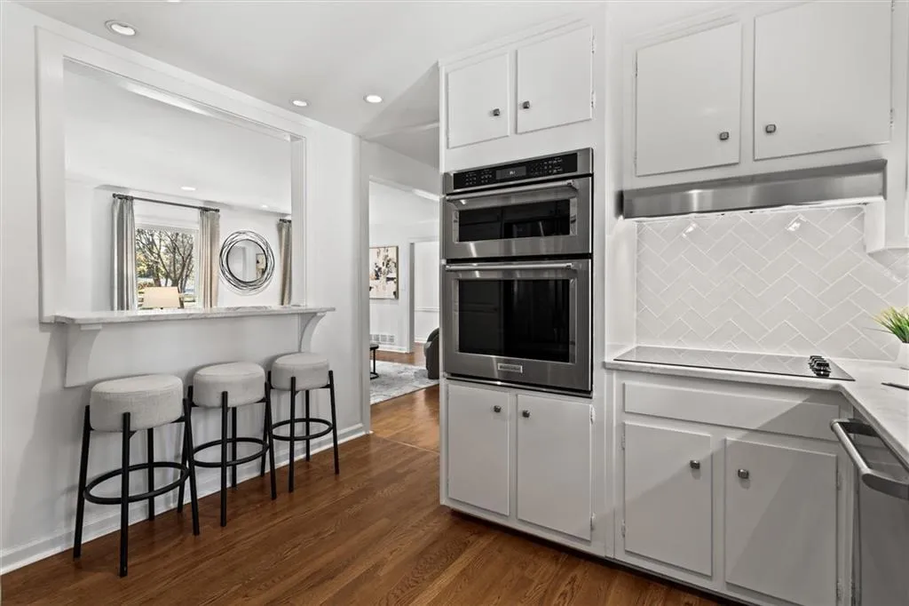 Kitchen featuring appliances with stainless steel finishes, white cabinetry, a breakfast bar, tasteful backsplash, and dark wood-type flooring