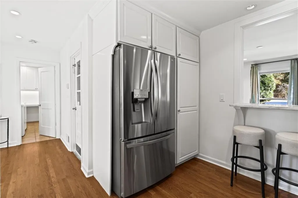 Kitchen featuring stainless steel fridge with ice dispenser, recessed lighting, dark wood-style floors, and a kitchen bar
