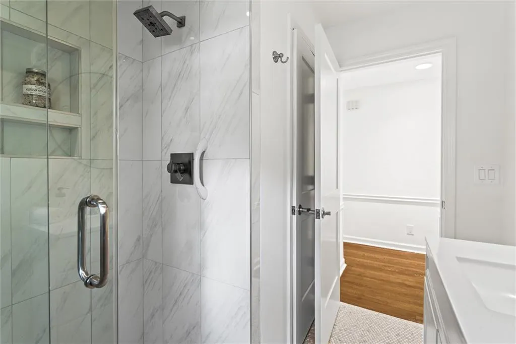 Full bathroom with a marble finish shower, vanity, and dark wood-type flooring