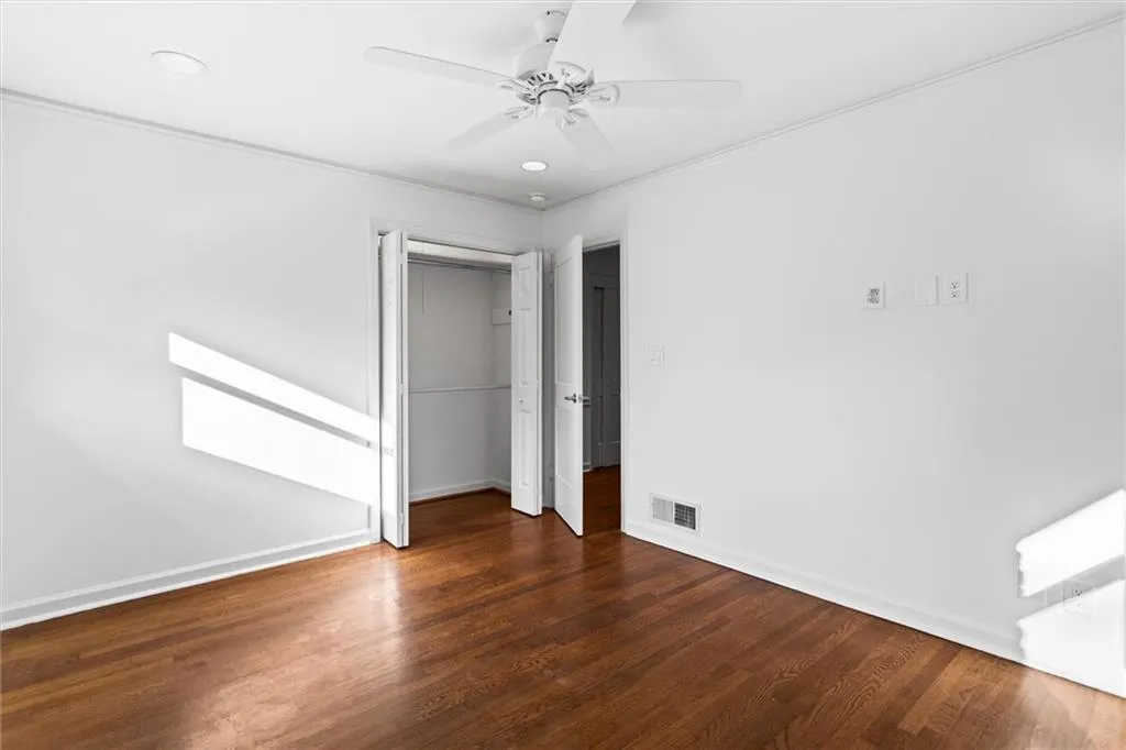 Unfurnished bedroom with dark wood-style floors, ceiling fan, a closet, crown molding, and recessed lighting