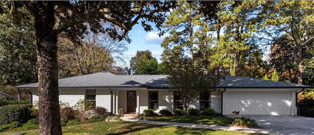 Ranch-style house featuring concrete driveway, brick siding, a porch, an attached garage, and a front yard