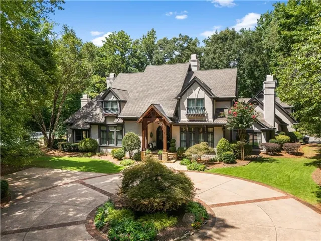 Tudor-style residence featuring a prominent gabled roofline, multiple chimneys, and decorative half-timbering