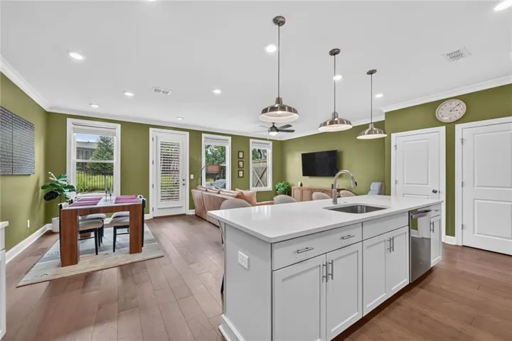 Spacious living area featuring wood-finish flooring, a ceiling fan, and crown molding