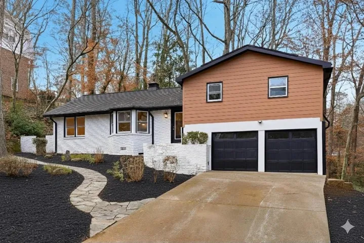 Split level home with brick siding, driveway, an attached garage, a chimney, and crawl space