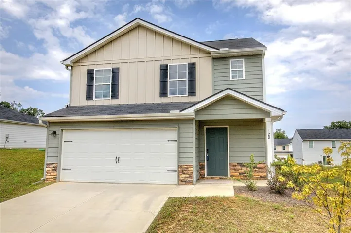 Two-story exterior with mixed siding, stone accents, attached garage, covered entryway, and front landscaping
