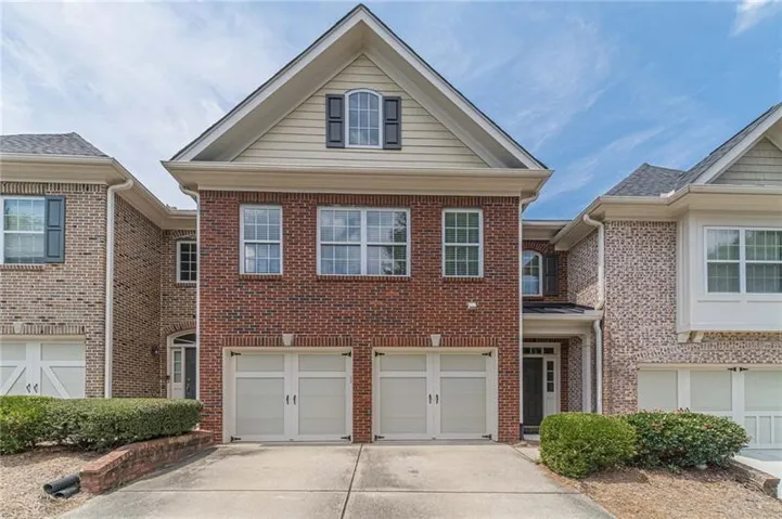 Brick and siding exterior, two-car garage, arched entry, gabled roofline, and dormer window