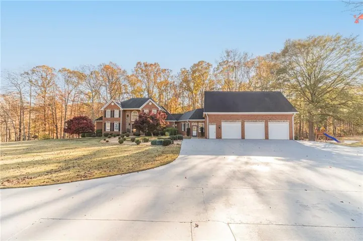 Brick exterior with dark shutters, three-car garage, and a concrete driveway