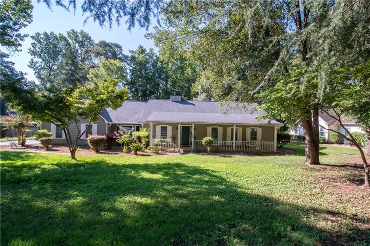 Single-story exterior with gray siding, white shutters, and a covered front porch featuring white railings