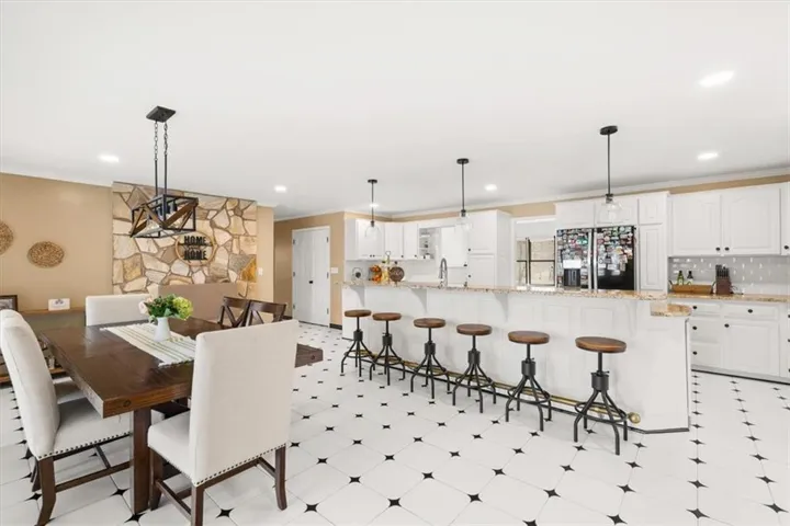 Kitchen featuring white cabinetry, light-toned countertops, a patterned tile backsplash, and pendant lighting