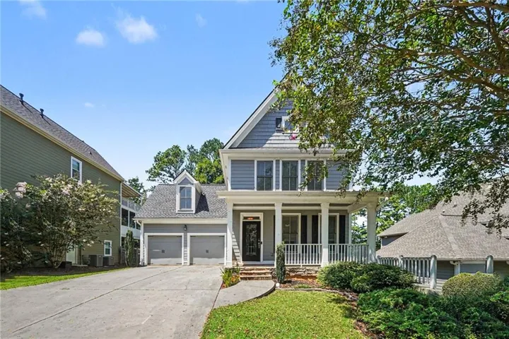 Traditional-style residence featuring a prominent front porch, shingle siding, a two-car garage, and a concrete driveway
