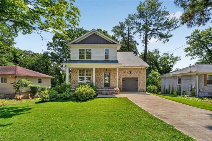 Two-story residence featuring a brick and siding exterior, covered front porch with columns, a two-car garage, and a concrete driveway