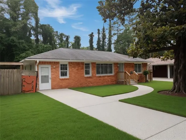 Brick exterior with a gray shingle roof, concrete drive, wood-finish porch, and a groomed lawn