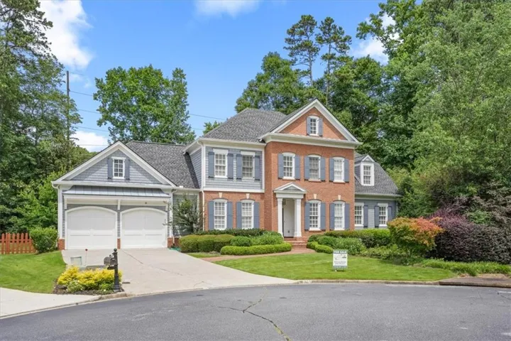 Traditional-style residence featuring a brick facade with light blue siding and a two-car garage