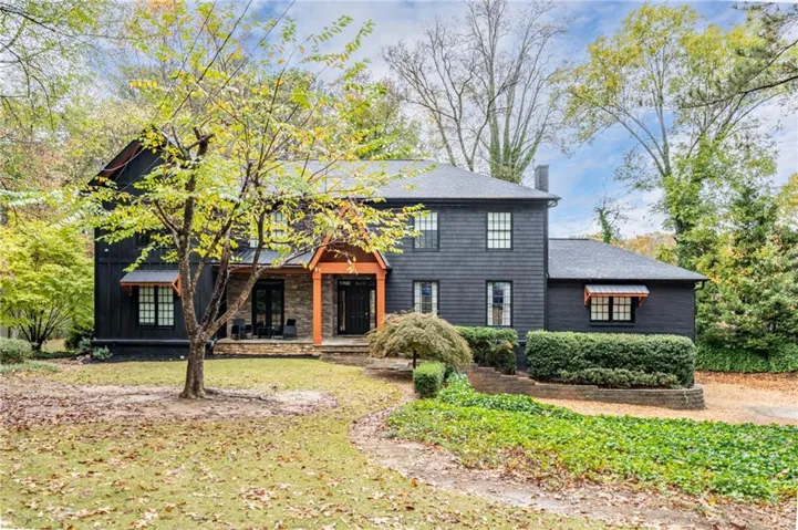 View of front facade with a front lawn, a chimney, and a shingled roof
