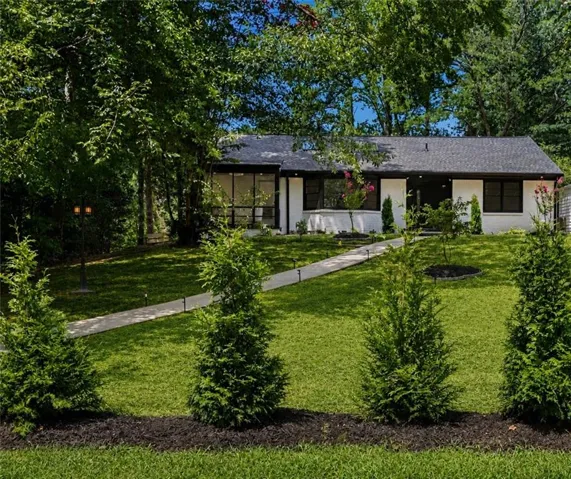 White exterior with black trim, dark shingle roof, and large windows