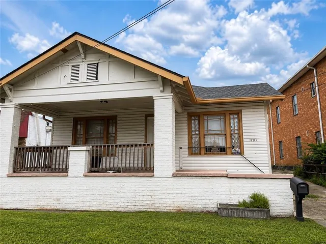 White siding exterior with a covered front porch featuring a wood railing