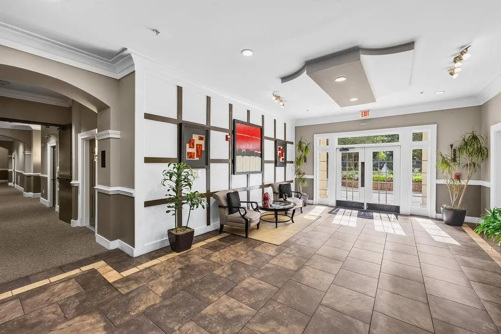 Spacious entry with tile flooring, double glass panel doors, transom windows, recessed lighting, and decorative wall paneling