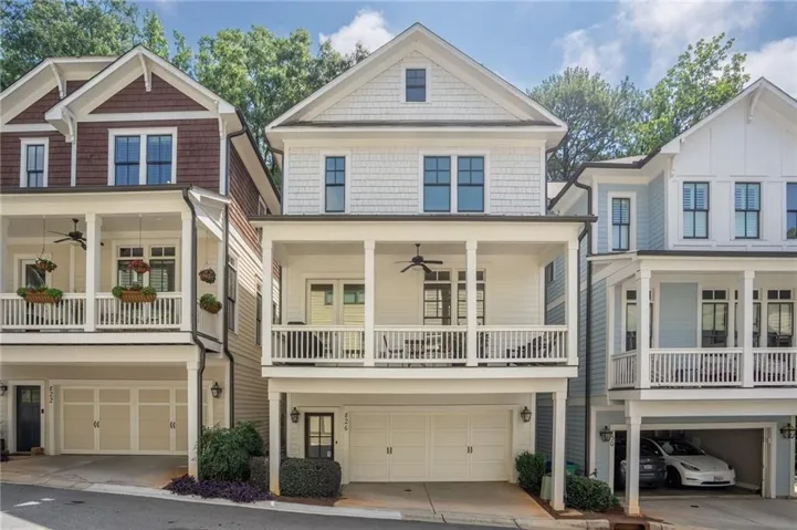 Contemporary townhouse exterior featuring a two-car garage, upper-level covered porch, and white balustrade railing