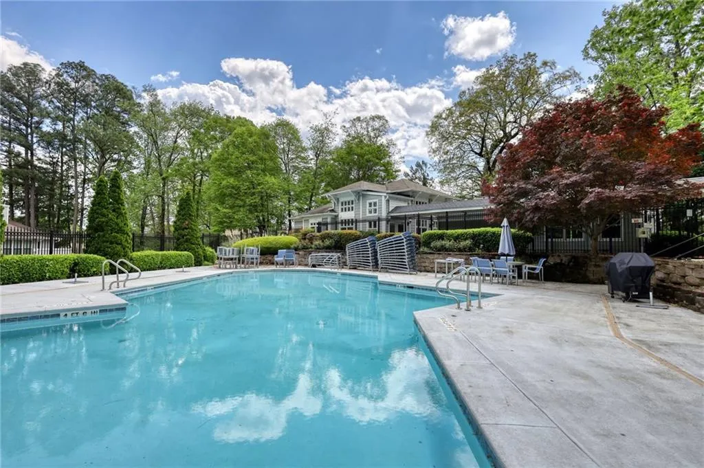 Community pool featuring a patio area, area for grilling, and view of scattered trees