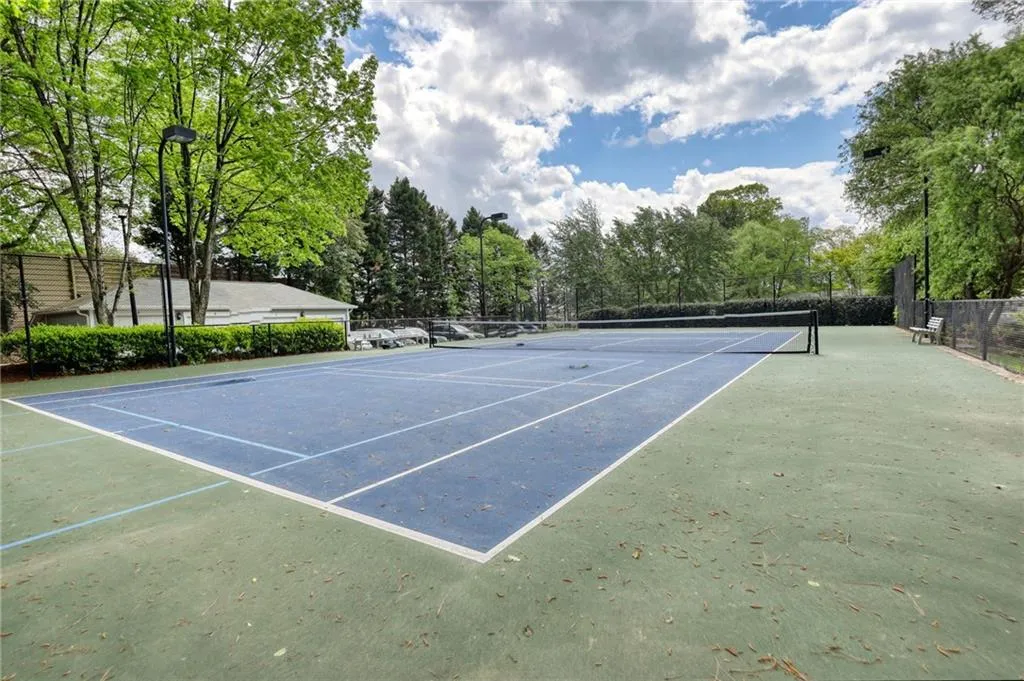 View of tennis court with view of wooded area