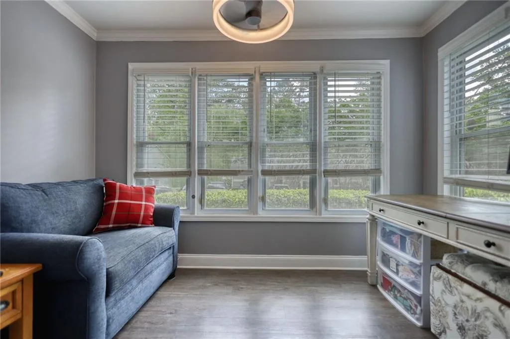 Sitting room with healthy amount of natural light, dark wood-style flooring, and ornamental molding