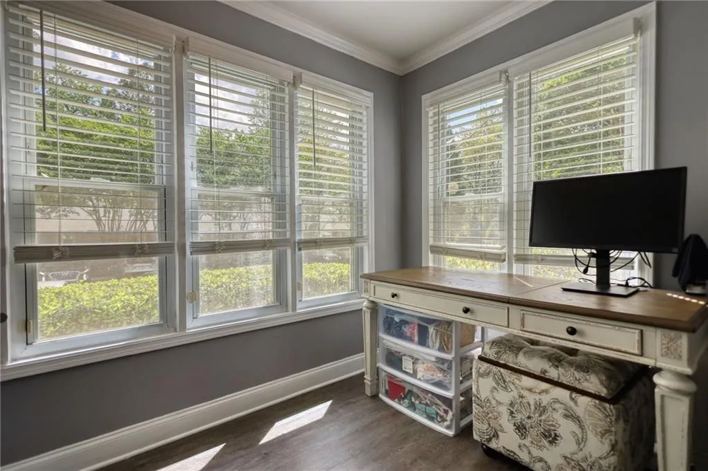 Office space featuring plenty of natural light, crown molding, and dark wood-style floors
