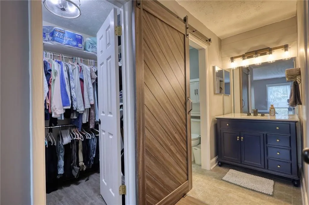 Bathroom featuring vanity, a textured ceiling, and a walk in closet