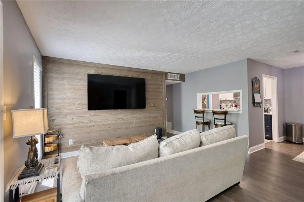 Living room featuring dark wood finished floors, an accent wall, wooden walls, and a textured ceiling