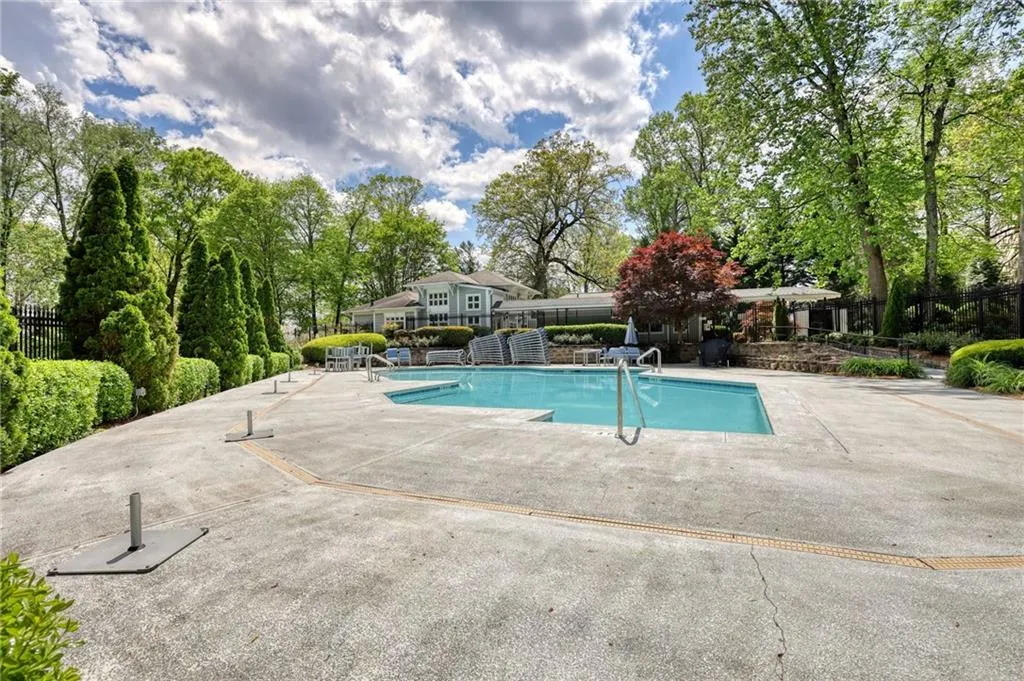 Community pool with view of wooded area and a patio area