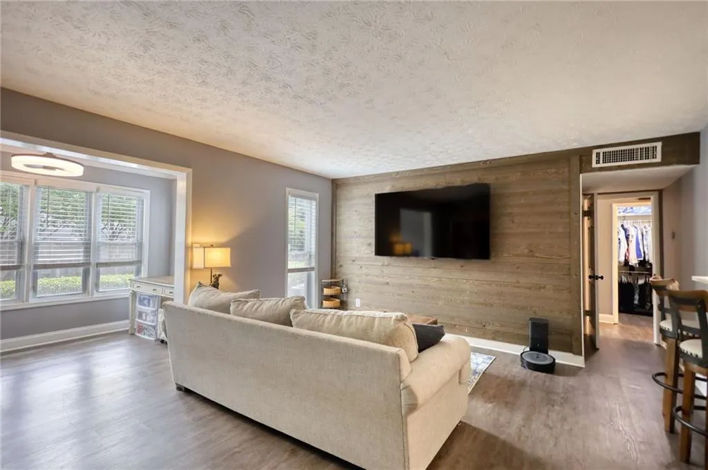 Living room with wood walls, healthy amount of natural light, a textured ceiling, and wood finished floors