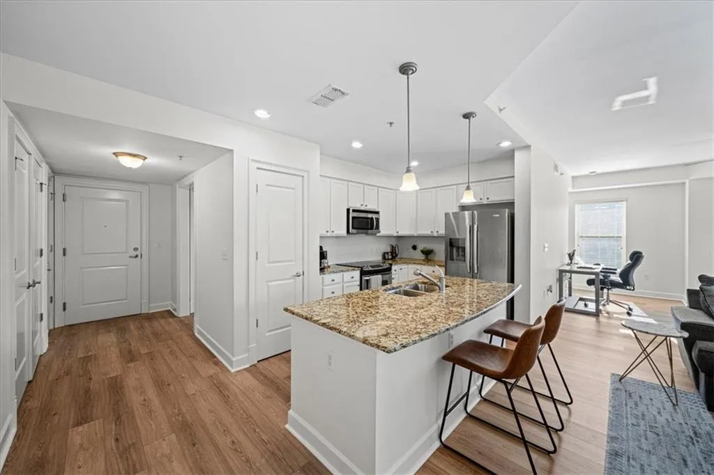 Kitchen featuring sink, stainless steel appliances, pendant lighting, a center island with sink, and white cabinets