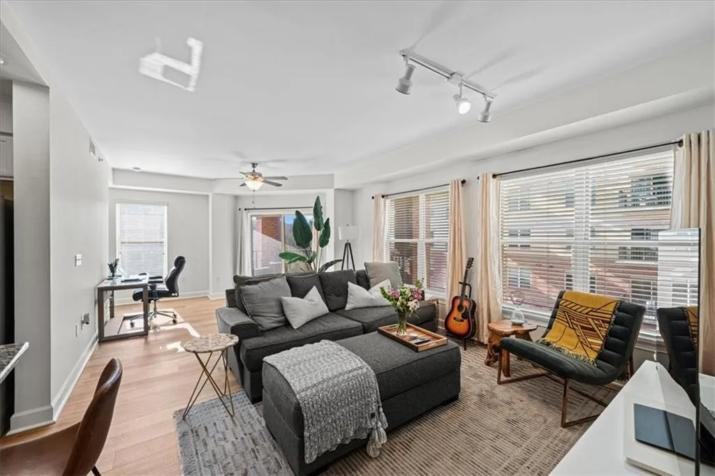 Living room featuring light wood-type flooring, rail lighting, and ceiling fan