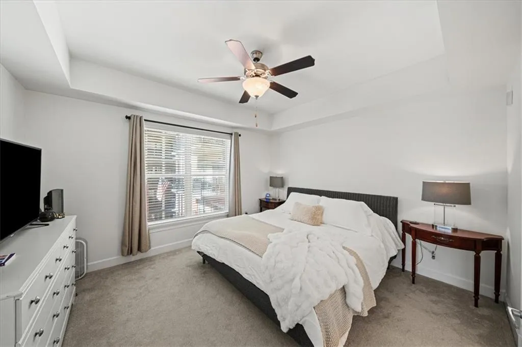 Carpeted bedroom with ceiling fan and a raised ceiling