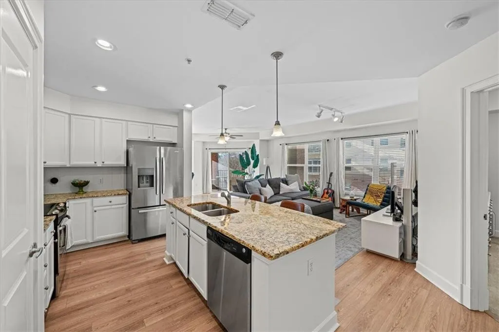 Kitchen with ceiling fan, sink, a center island with sink, white cabinets, and appliances with stainless steel finishes