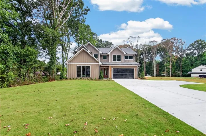 Contemporary two-story residence featuring a two-car garage with a dark finish door, a substantial concrete driveway, and a manicured lawn